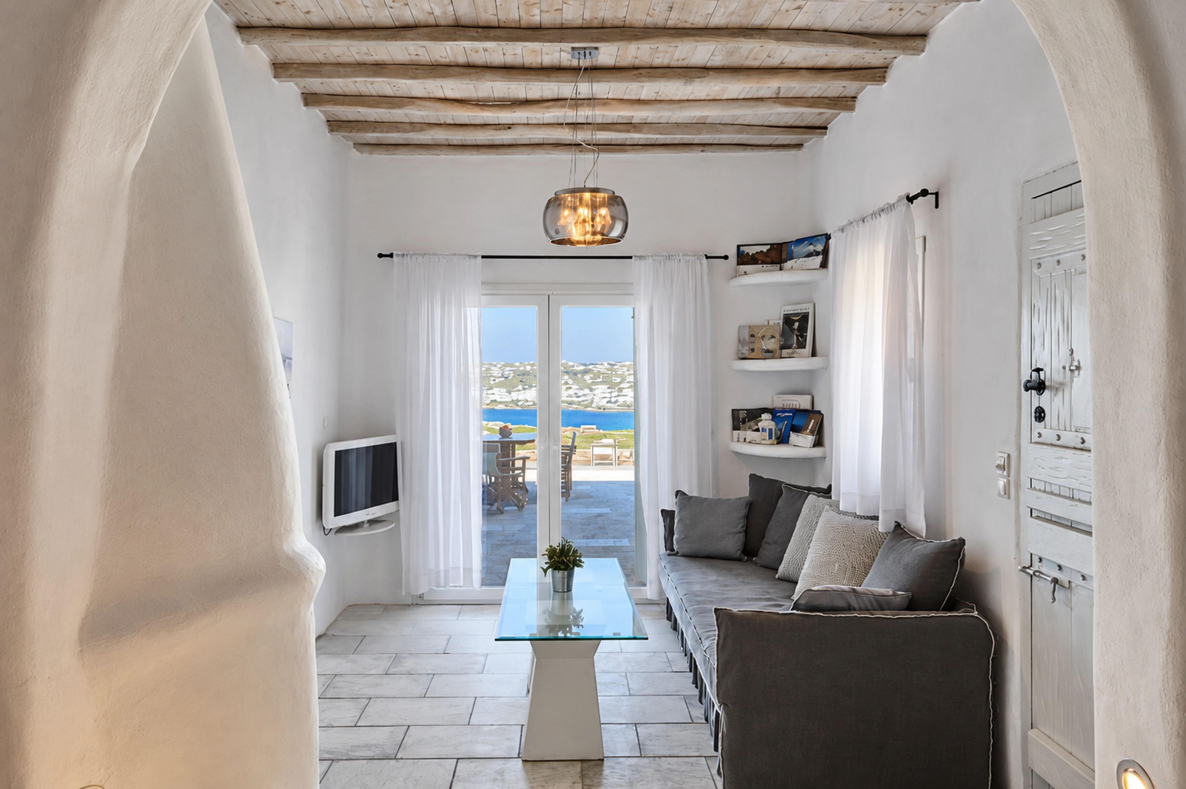 Nalu’s whitewashed living room, with wooden ceiling beams and a glimpse of the sea