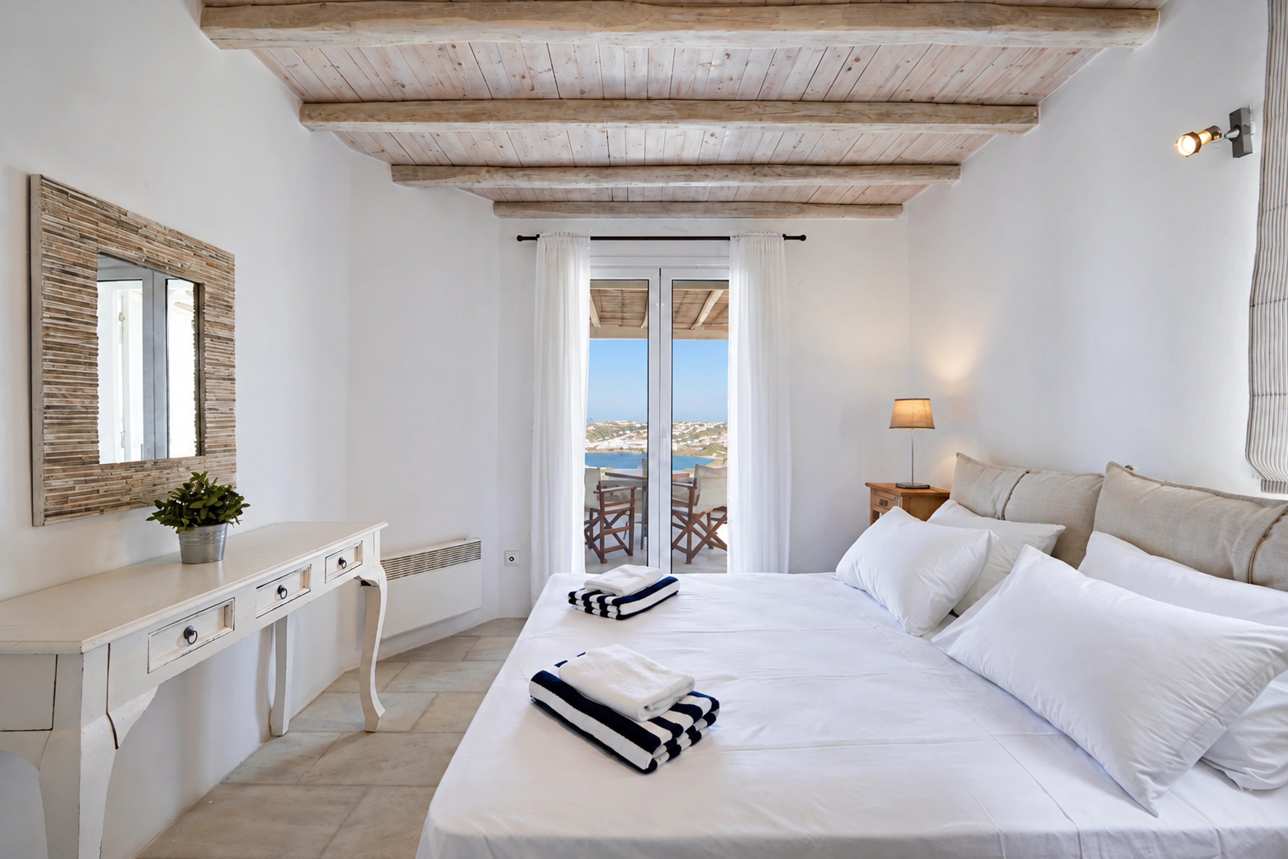 Nalu’s bedroom with white linen, natural ceiling beams and a sea-view balcony