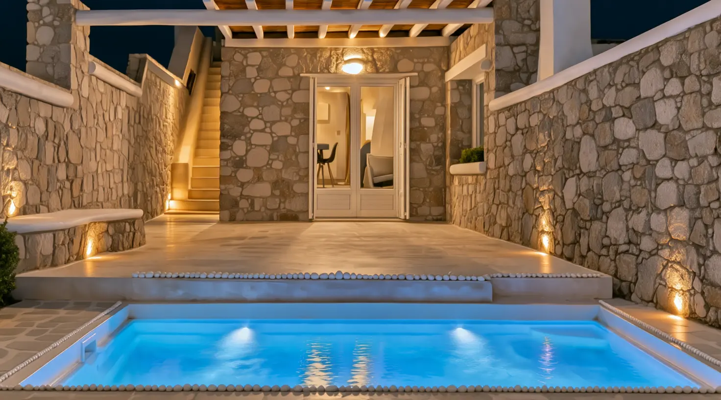 Nalu Villa at night, with warm lights on the stone facade and its illuminated private pool